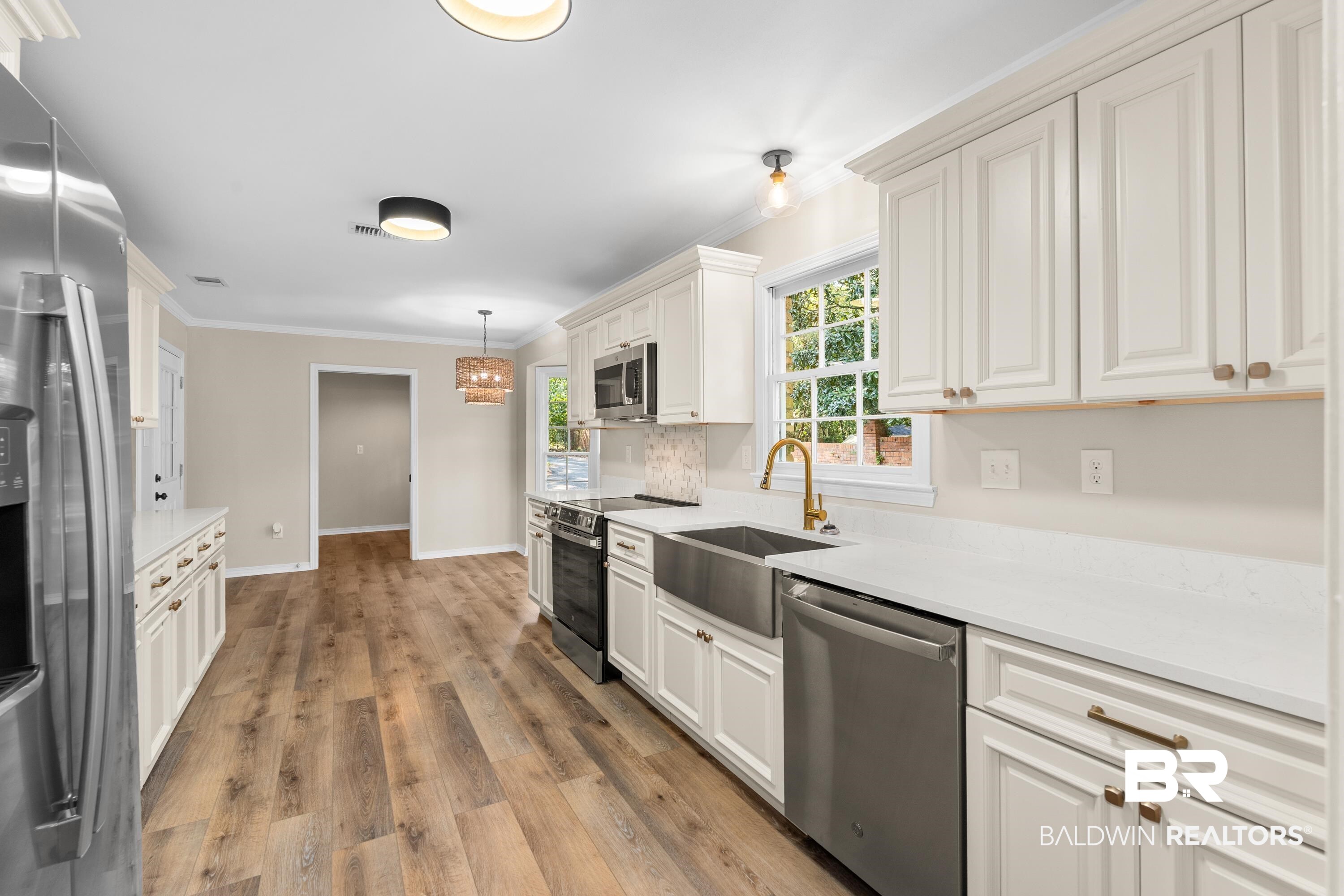 728 Spring Station Road Mobile, AL 36609 - Photo 7 of 35 Kitchen with stainless steel appliances, crown molding, light wood-style floors, hanging light fixtures, and light stone counters