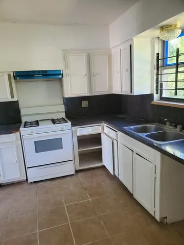 a kitchen with granite countertop a stove top oven sink and cabinets