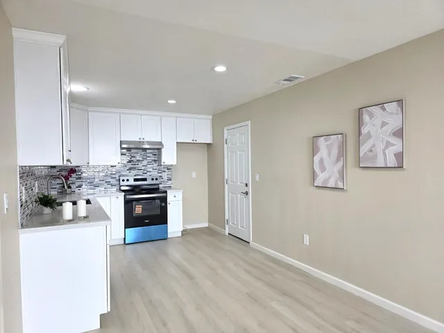 a kitchen with stainless steel appliances granite countertop a stove and white cabinets