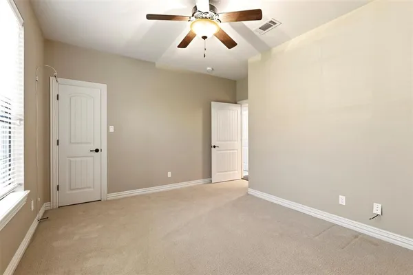 an empty room with windows and fan