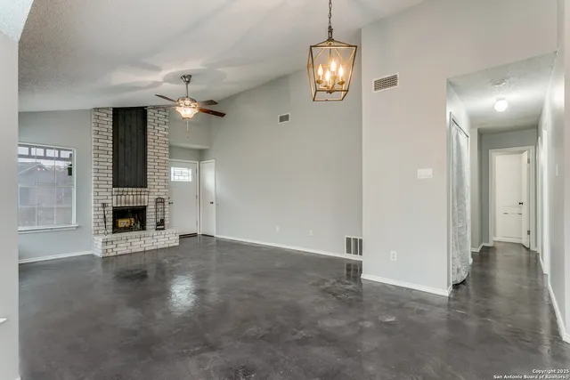 an empty room with a fireplace and chandelier fan