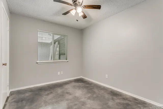 an empty room with windows and fan