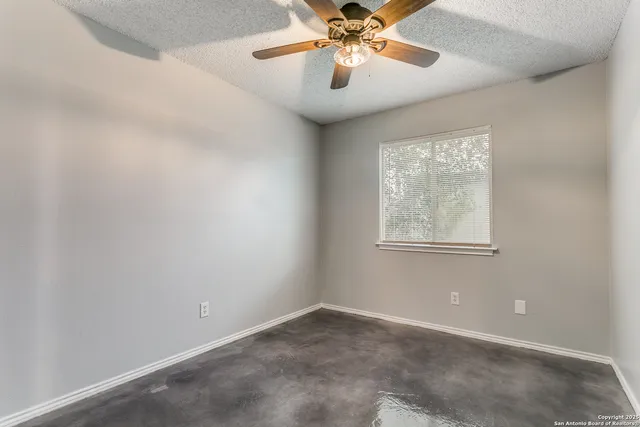 an empty room with windows and fan