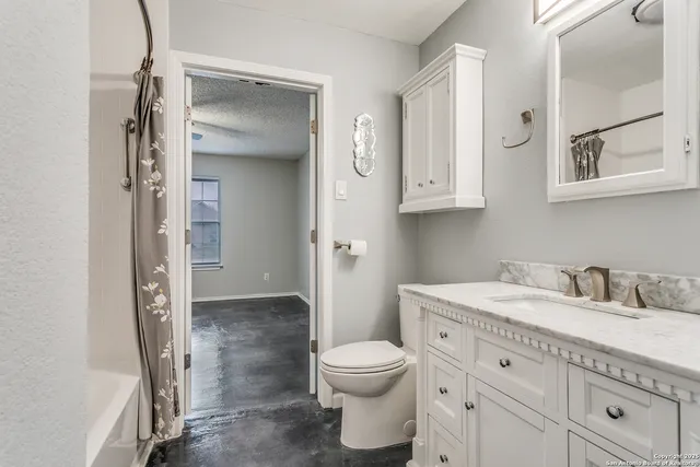 a bathroom with a granite countertop sink toilet a mirror and shower