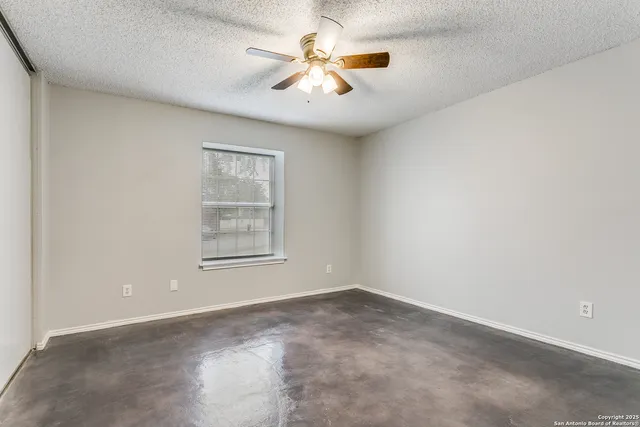 en empty room with windows and chandelier fan