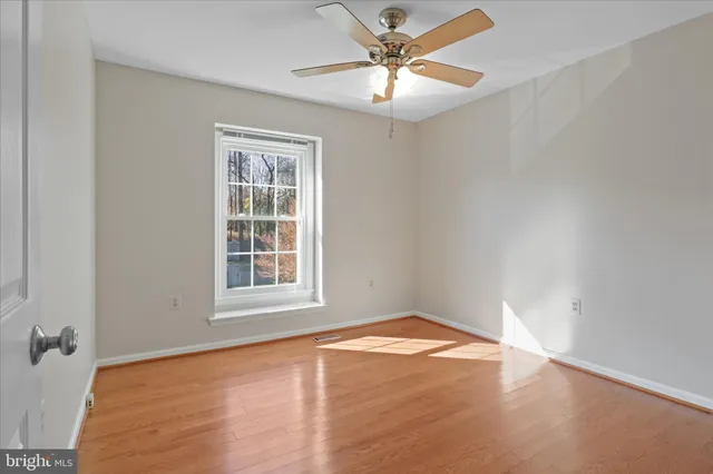an empty room with a chandelier fan and windows