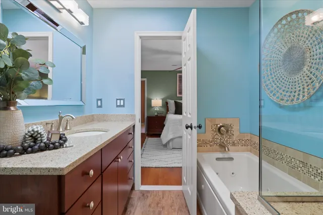 a bathroom with a granite countertop tub sink and mirror