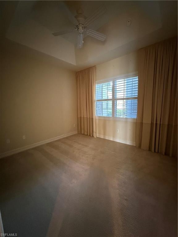 7168 Lemuria Circle, Unit 1701 Naples, FL 34109 - Photo 15 of 30 Spare room with a tray ceiling, a ceiling fan, and carpet flooring