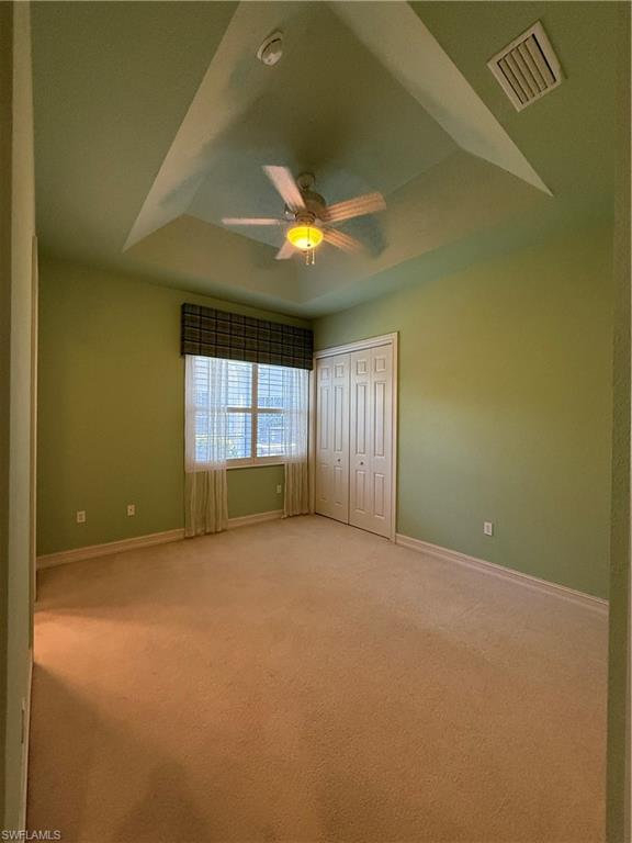 7168 Lemuria Circle, Unit 1701 Naples, FL 34109 - Photo 18 of 30 Unfurnished bedroom featuring a tray ceiling, light colored carpet, a closet, and ceiling fan