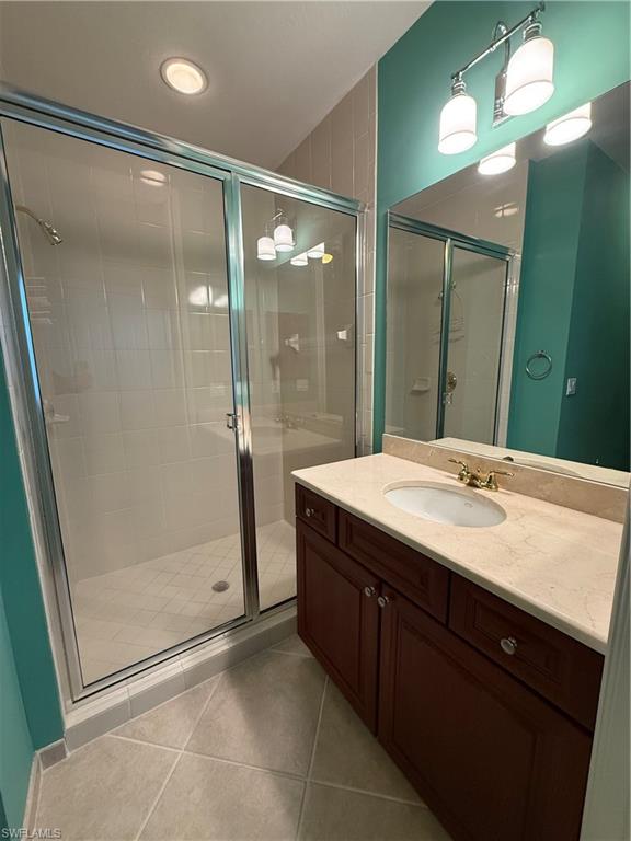 7168 Lemuria Circle, Unit 1701 Naples, FL 34109 - Photo 19 of 30 Full bath featuring a stall shower, vanity, and light tile patterned floors
