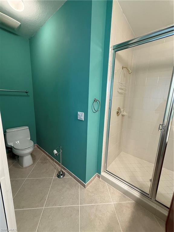 7168 Lemuria Circle, Unit 1701 Naples, FL 34109 - Photo 20 of 30 Full bathroom featuring a stall shower, light tile patterned floors, and a textured ceiling