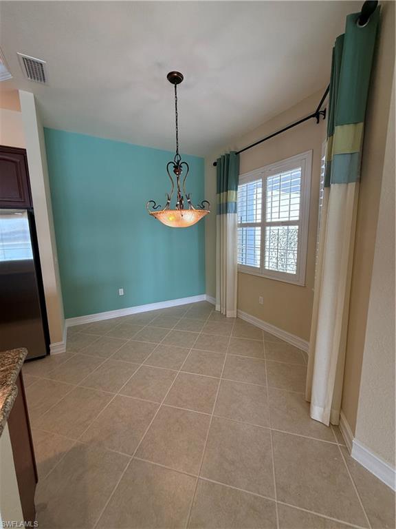 7168 Lemuria Circle, Unit 1701 Naples, FL 34109 - Photo 2 of 30 Unfurnished dining area with light tile patterned floors and a chandelier
