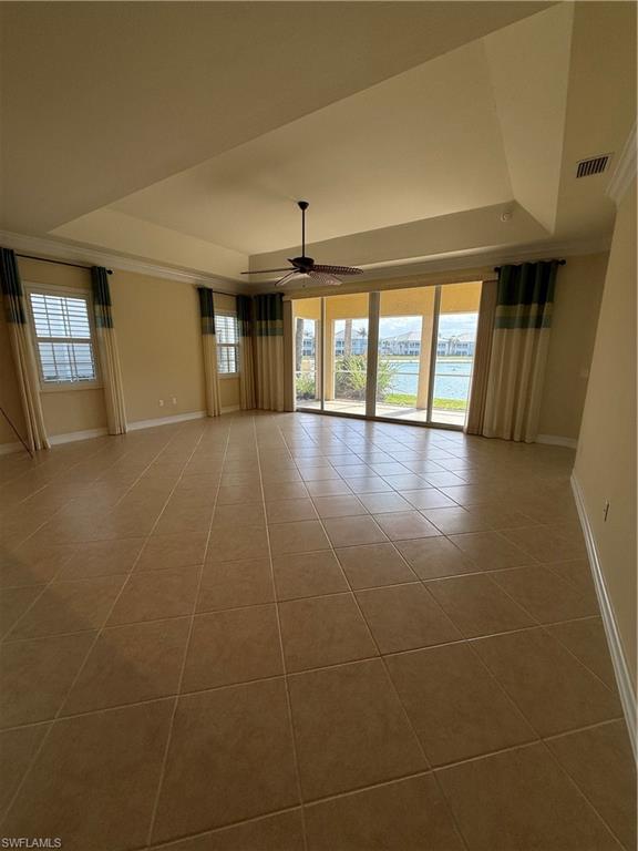 7168 Lemuria Circle, Unit 1701 Naples, FL 34109 - Photo 21 of 30 Empty room featuring a tray ceiling, ceiling fan, light tile patterned flooring, a water view, and crown molding
