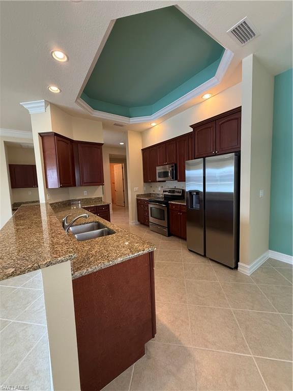 7168 Lemuria Circle, Unit 1701 Naples, FL 34109 - Photo 3 of 30 Kitchen featuring stainless steel appliances, dark stone countertops, a peninsula, a raised ceiling, and crown molding