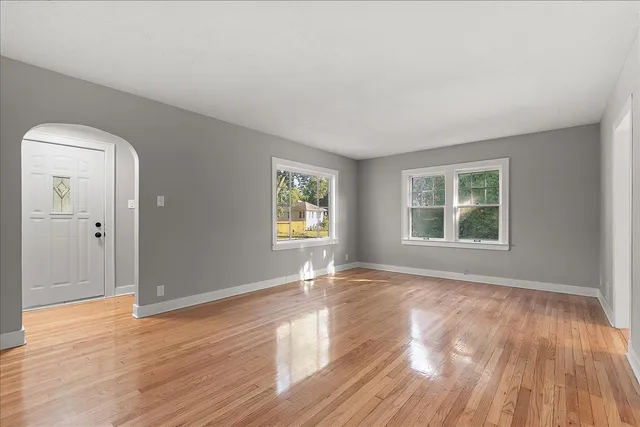 a view of an empty room with wooden floor and a window