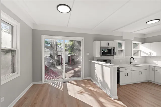 a kitchen with stainless steel appliances granite countertop a stove top oven a sink dishwasher a refrigerator and white cabinets with wooden floor