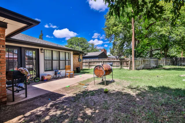 a backyard of a house with barbeque oven table and chairs
