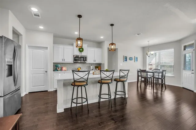 a view of a dining room and livingroom with furniture wooden floor a chandelier