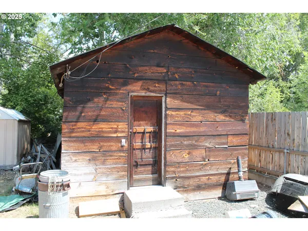a backyard of a house with wooden fence and large trees
