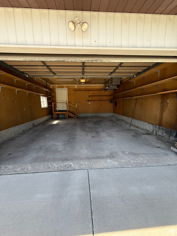 328 Heather Ridge Circle Sandy, UT 84070 - Photo 20 of 32 Spacious garage featuring a concrete floor, built-in shelving, overhead lighting, and an access door with a small landing and steps