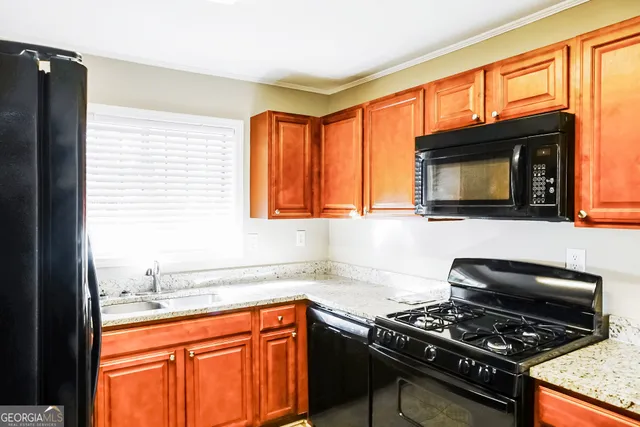 a kitchen with granite countertop a stove top oven a sink dishwasher and a microwave oven with cabinets
