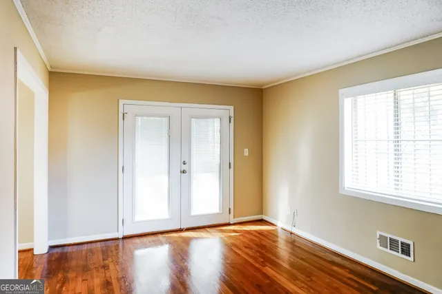 a view of an empty room with wooden floor and a window
