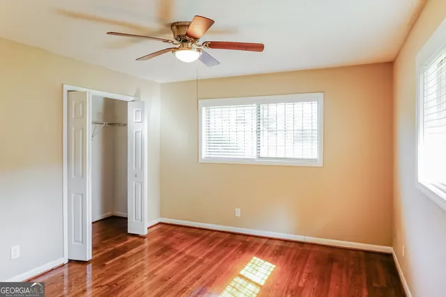 a view of an empty room with wooden floor and a window