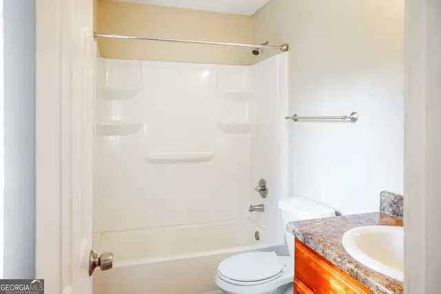 a bathroom with a granite countertop bathtub shower sink vanity and toilet