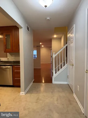 a view of an empty room with kitchen and window