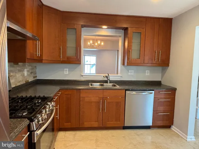 a kitchen with stainless steel appliances granite countertop a stove a sink dishwasher and cabinets with wooden floor