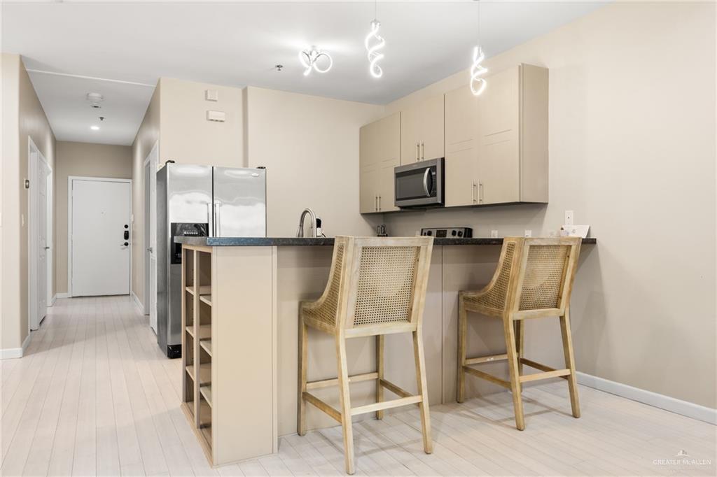 813 Travis Street, Unit 315 Mission, TX 78572 - Photo 7 of 25 a kitchen with stainless steel appliances kitchen island granite countertop a refrigerator and microwave