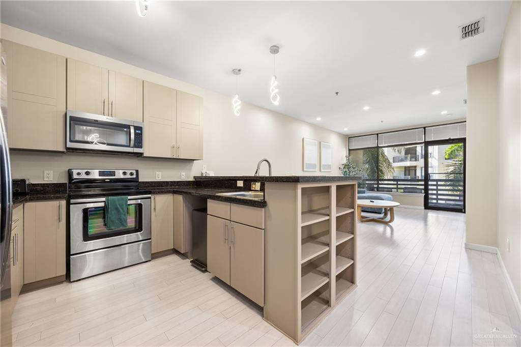 813 Travis Street, Unit 315 Mission, TX 78572 - Photo 8 of 25 a kitchen with stainless steel appliances kitchen island granite countertop a stove a sink and a microwave