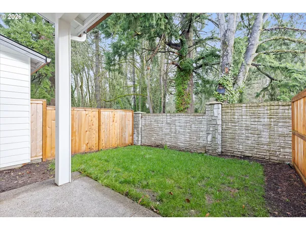 a view of a yard with brick wall and a large tree