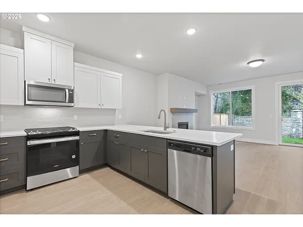 a kitchen with stainless steel appliances granite countertop a sink a stove a microwave a sink a refrigerator and cabinets