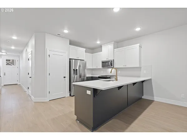 a kitchen with a sink a refrigerator and white cabinets
