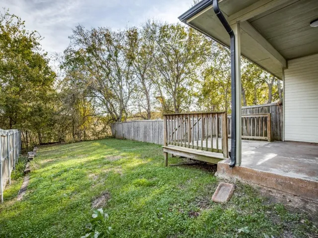 a view of a backyard with wooden fence and a bench
