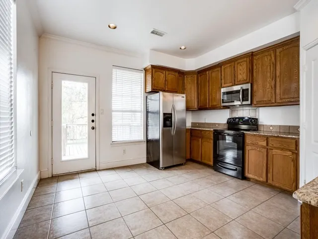 a kitchen with granite countertop a refrigerator and a stove top oven