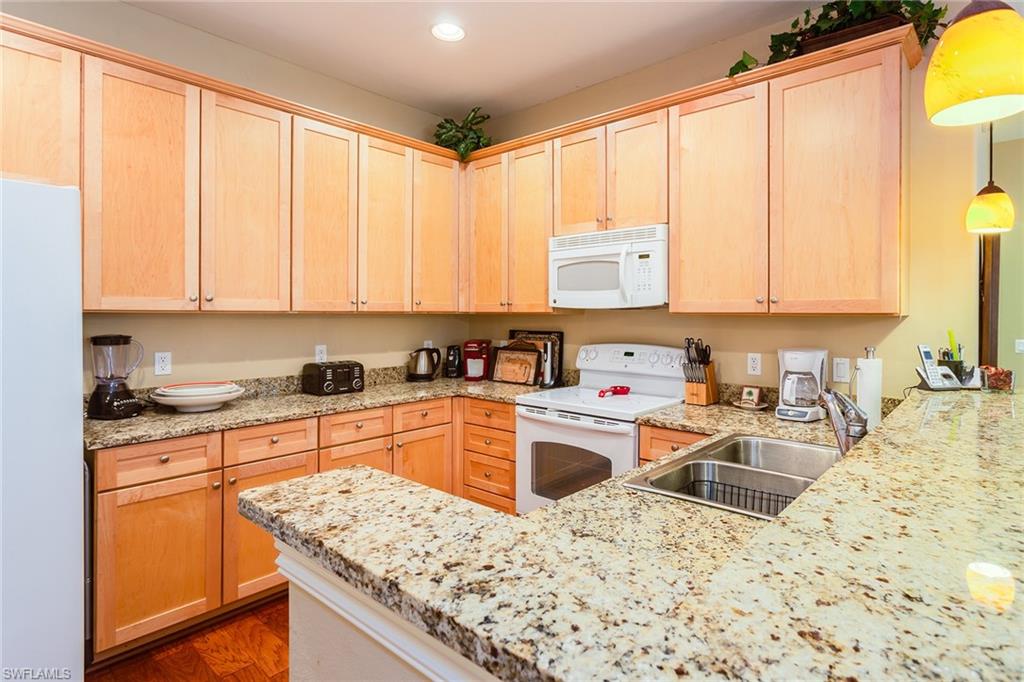 9088 Chula Vista Street, Unit 1083 Naples, FL 34113 - Photo 11 of 31 a kitchen with stainless steel appliances granite countertop a sink stove and refrigerator