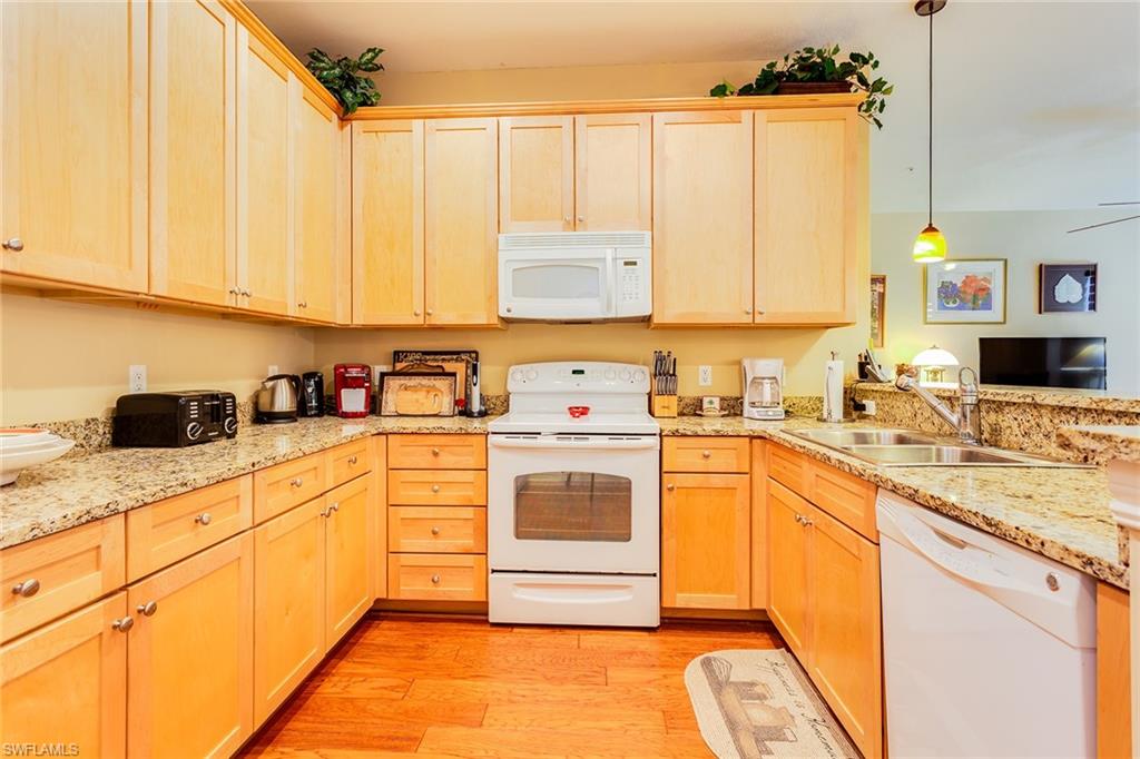 9088 Chula Vista Street, Unit 1083 Naples, FL 34113 - Photo 12 of 31 a kitchen with a white cabinets and white appliances