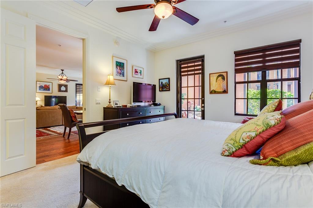 9088 Chula Vista Street, Unit 1083 Naples, FL 34113 - Photo 22 of 31 a bedroom with a bed and dresser with wooden floor