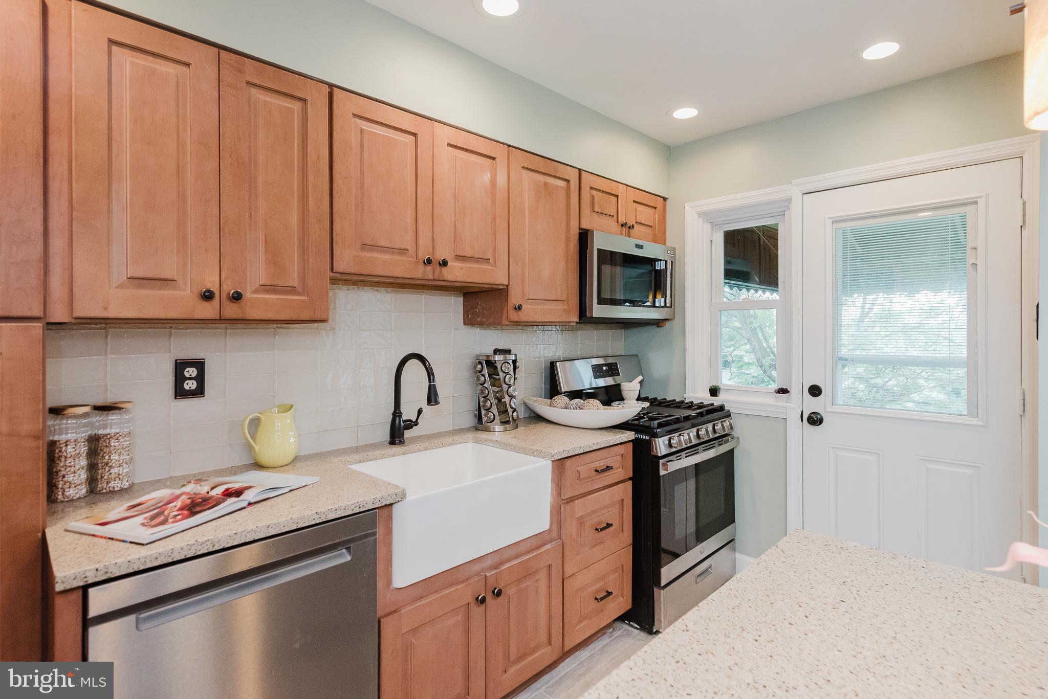 570 47th Street Baltimore, MD 21224 - Photo 12 of 41 a kitchen with stainless steel appliances granite countertop a stove top oven a sink dishwasher and a refrigerator with wooden cabinets