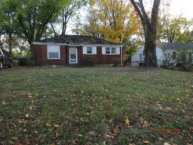 a view of a yard in front of a house with large trees