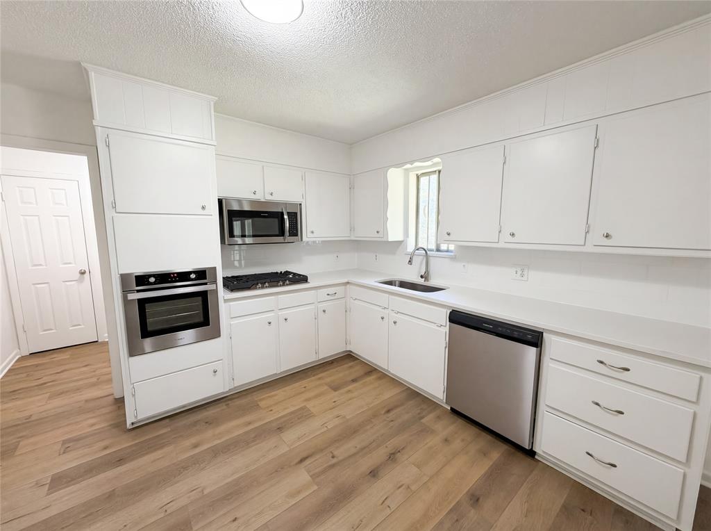 607 State Street Weatherford, TX 76086 - Photo 2 of 16 a kitchen with granite countertop white cabinets and white appliances