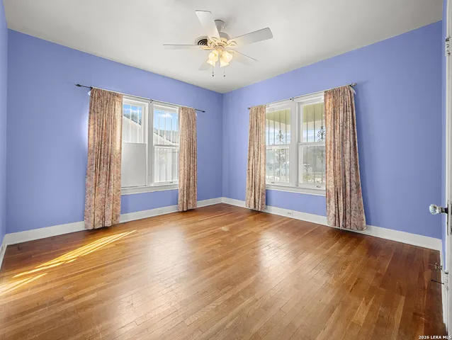 a view of an empty room with window and wooden floor