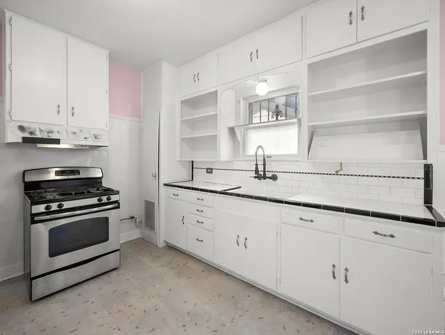 a kitchen with granite countertop white cabinets and stainless steel appliances