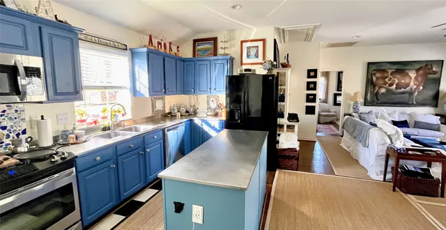 a large kitchen with stainless steel appliances kitchen island granite countertop a table chairs in it and a window