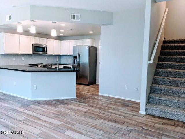 3150 East Beardsley Road, Unit 1045 Phoenix, AZ 85050 - Photo 3 of 23 a view of kitchen with stainless steel appliances granite countertop cabinets and wooden floor