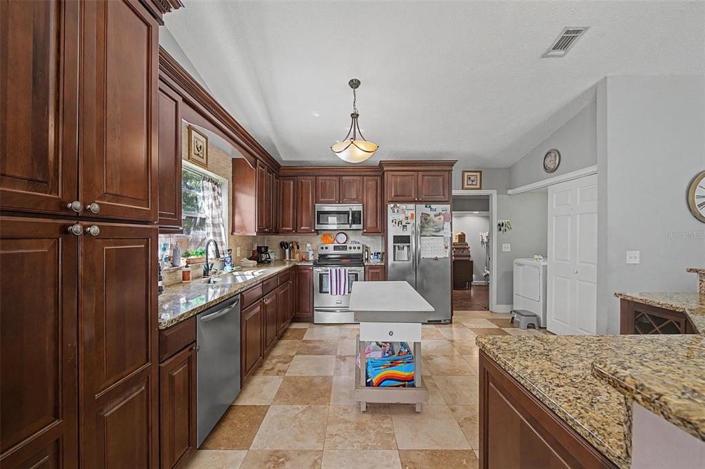 1632 Pintail Court Lutz, FL 33549 - Photo 12 of 34 a large kitchen with stainless steel appliances granite countertop a stove oven and a refrigerator with cabinets