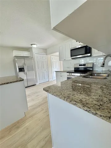 a kitchen with stainless steel appliances granite countertop a sink stove and microwave