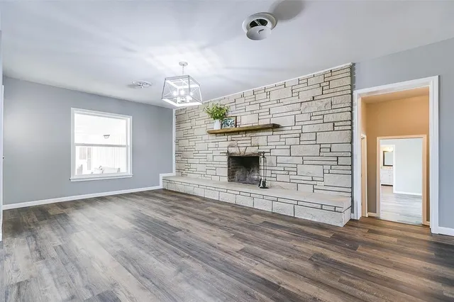 an empty room with wooden floor fireplace and window